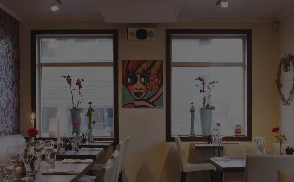 Matsalen på Restaurang Ester med dukade bord och orkidéer i fönstren